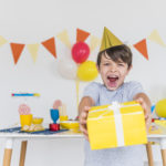 cheerful-boy-taking-yellow-gift-box-with-white-ribbon