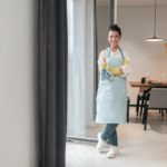 Smiling housewife in apron standing in the kitchen