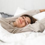 Smiling young girl relaxing in bed in the morning