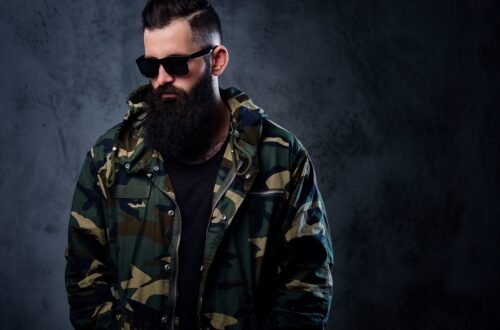 A man dressed in a camouflage jacket over grey background.